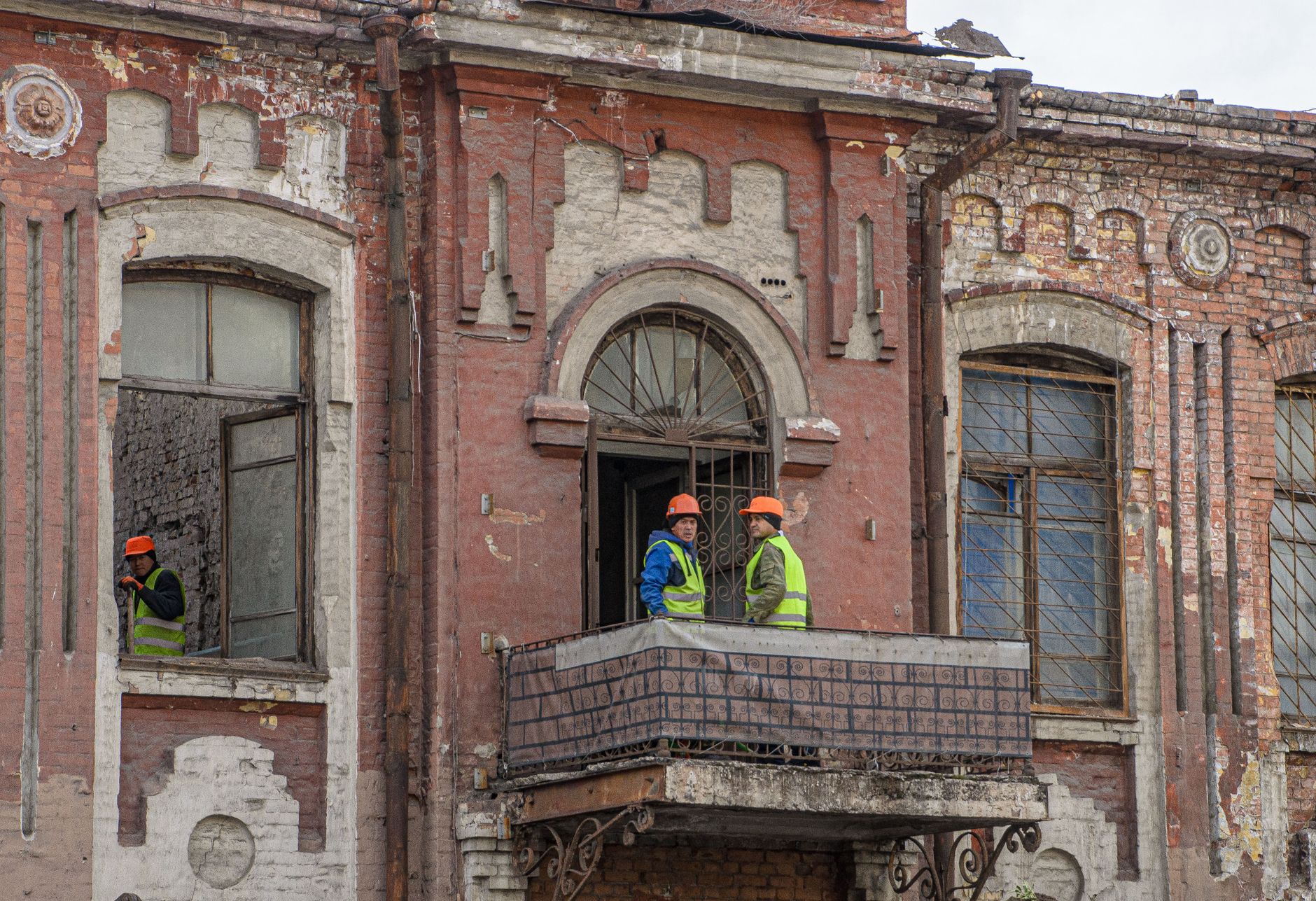 Construction workers renovating an old brick building with traditional architecture.