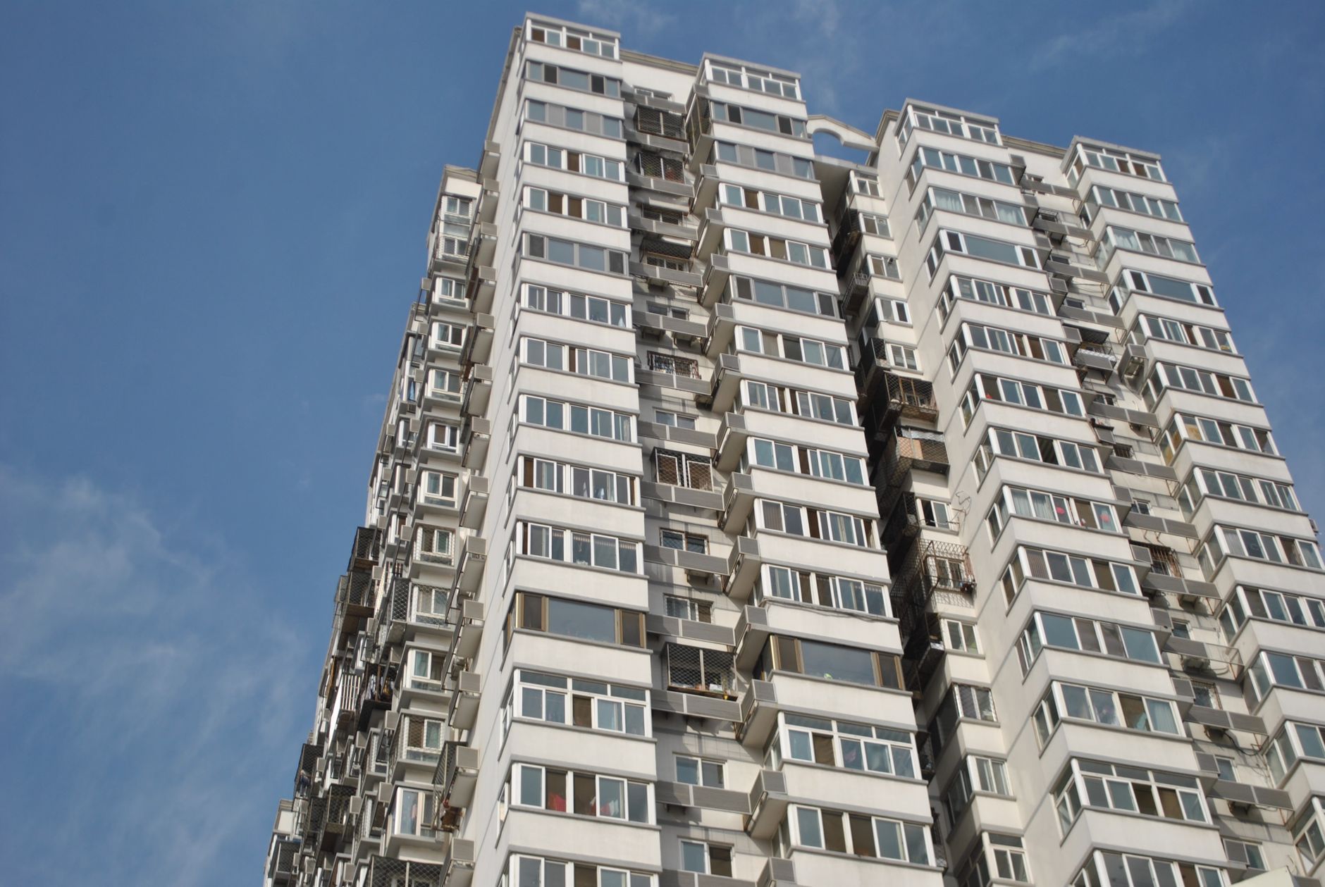 Modern high-rise apartment building with many windows under a clear blue sky.
