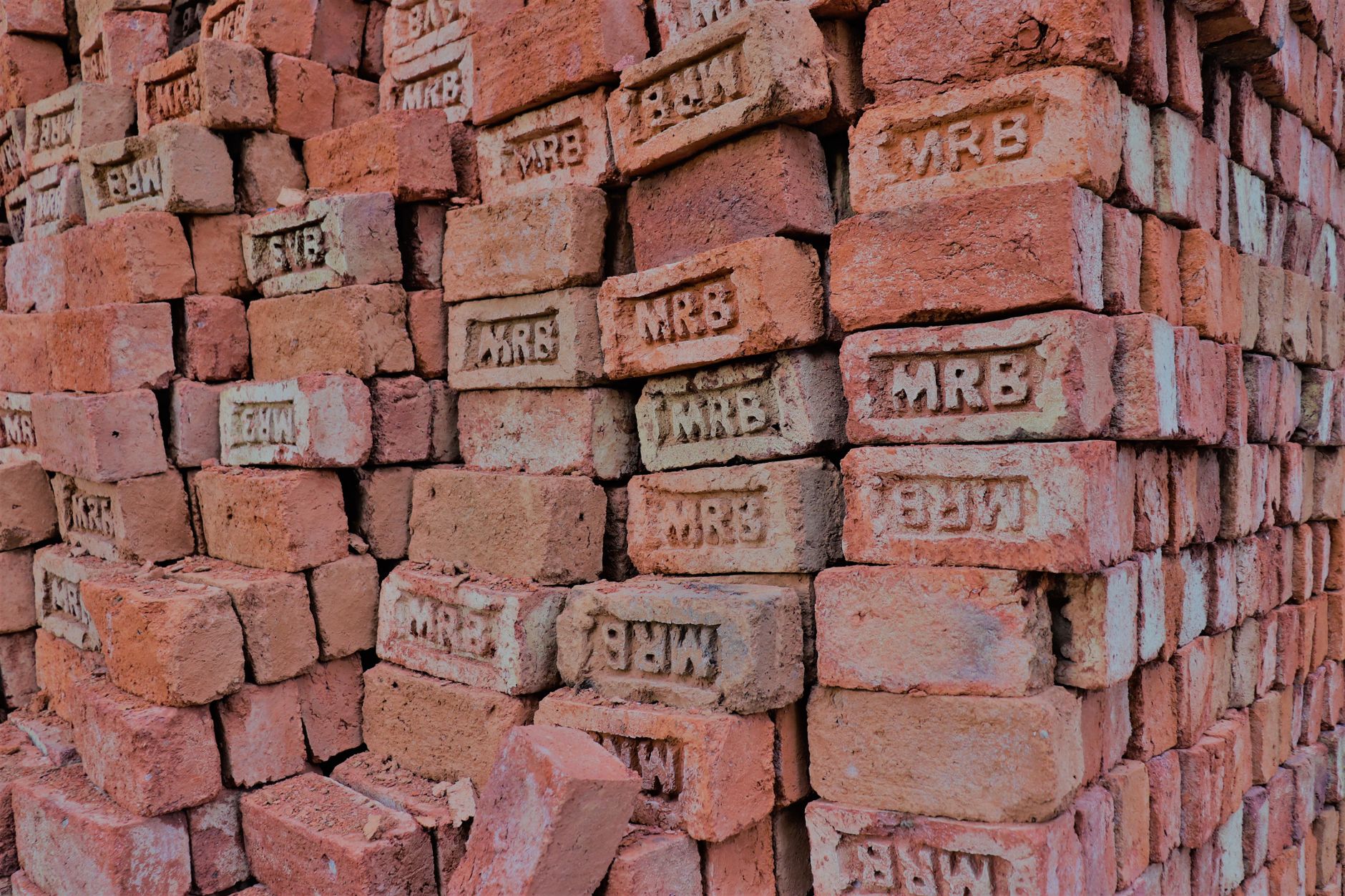 Stacks of red bricks labeled MRB at an outdoor construction site.