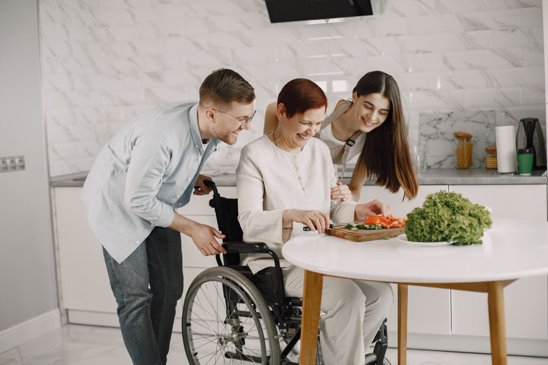 A joyful family preparing vegetables in a modern kitchen around a wheelchair-bound member.