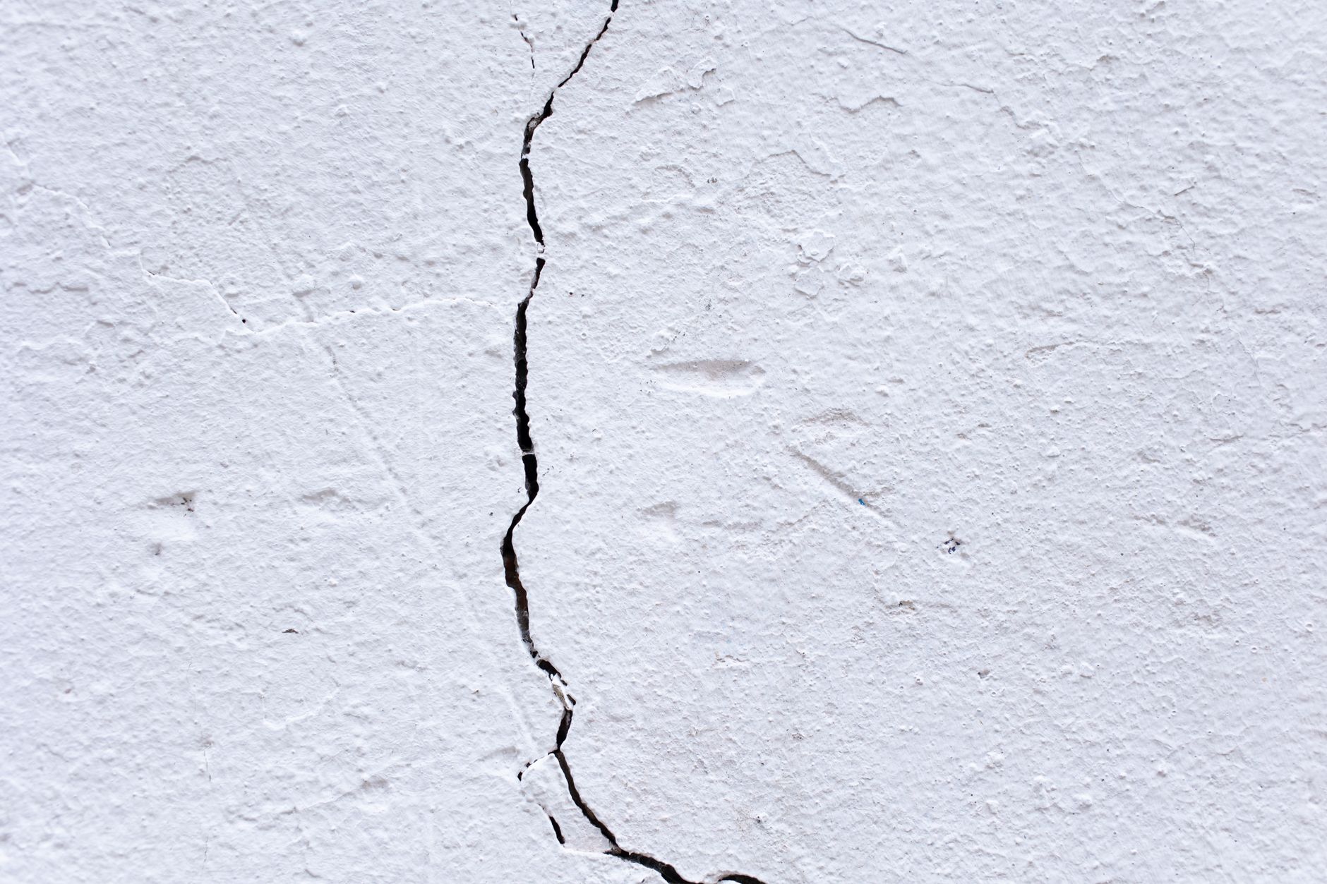 Backdrop of textured rough plaster wall with uneven surface and large crack in center