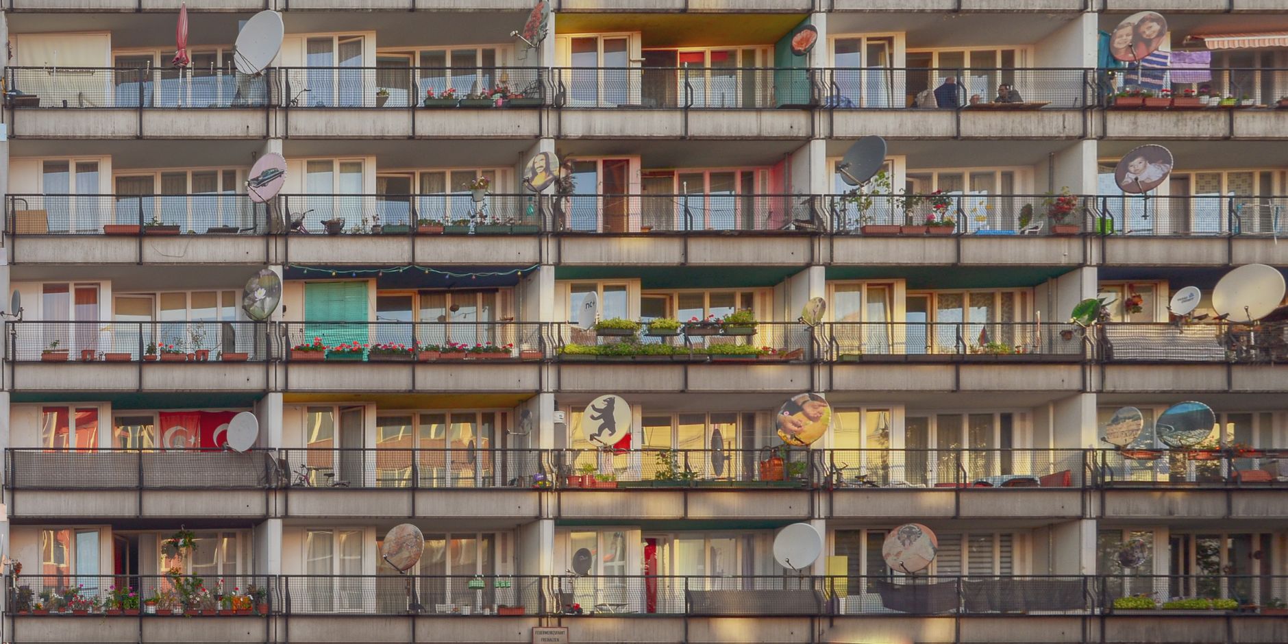 Photograph of a residential building with colorful balconies and satellite dishes in Berlin.
