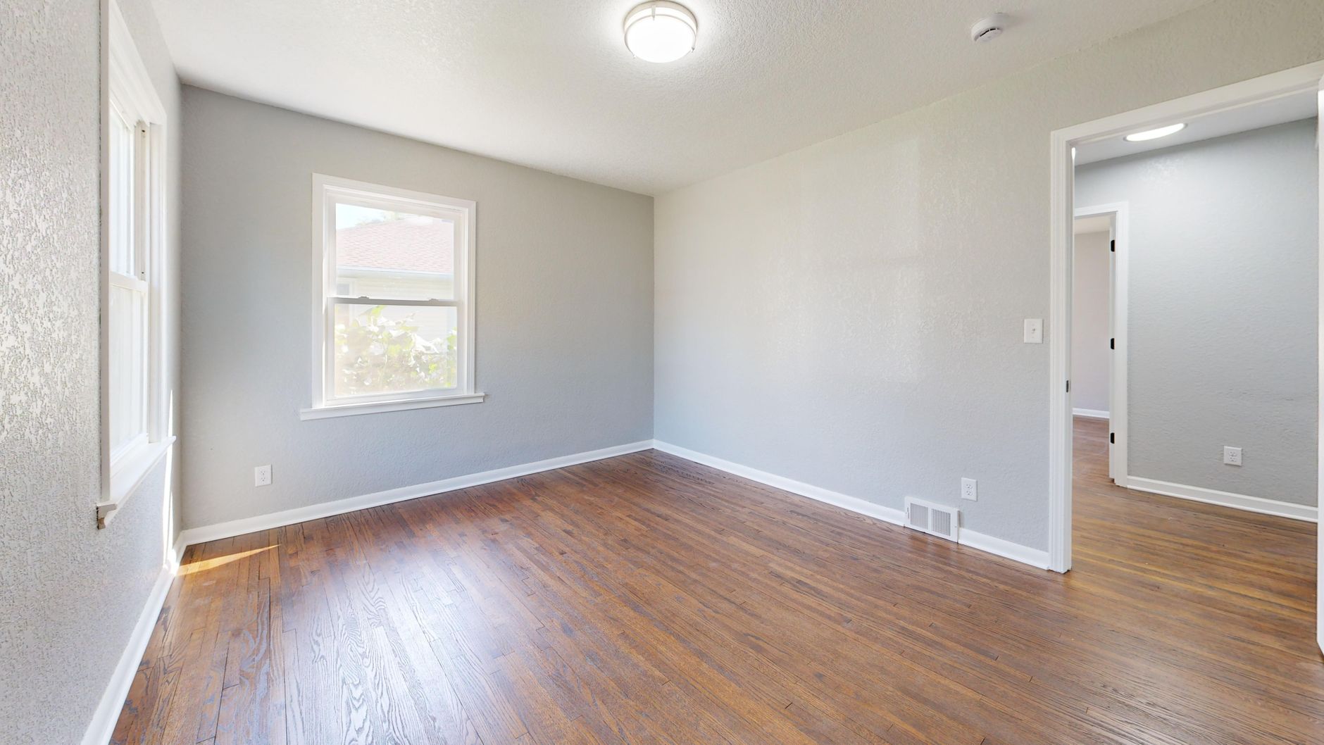 Spacious empty room featuring hardwood floors and natural light.