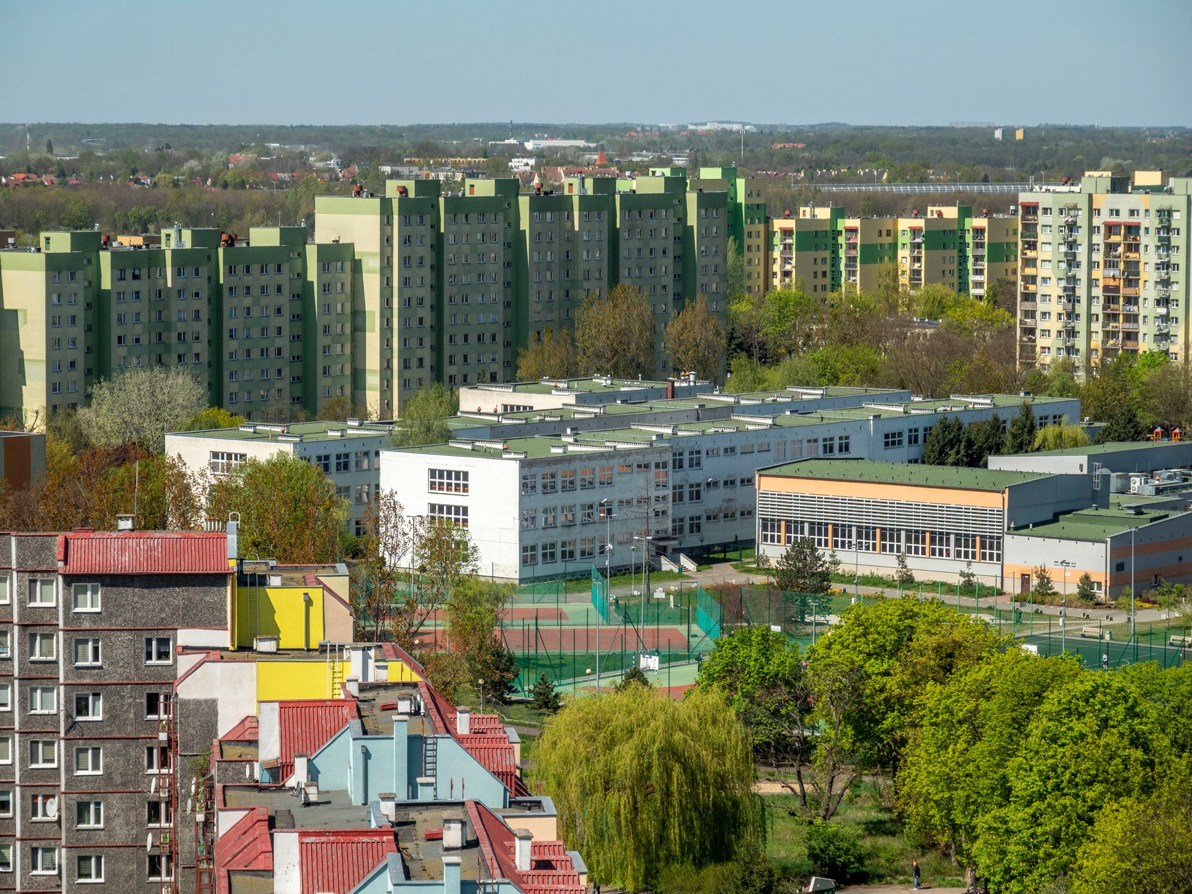 Aerial photograph of residential blocks and school in Wrocław, Poland, during daytime in spring.