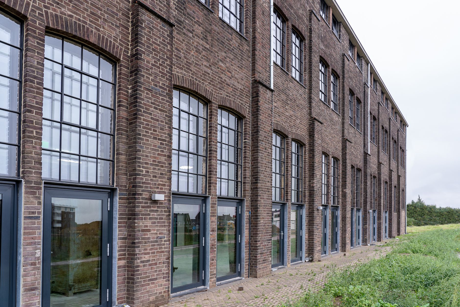 Side view of a historic brick building with large windows and modern renovation.
