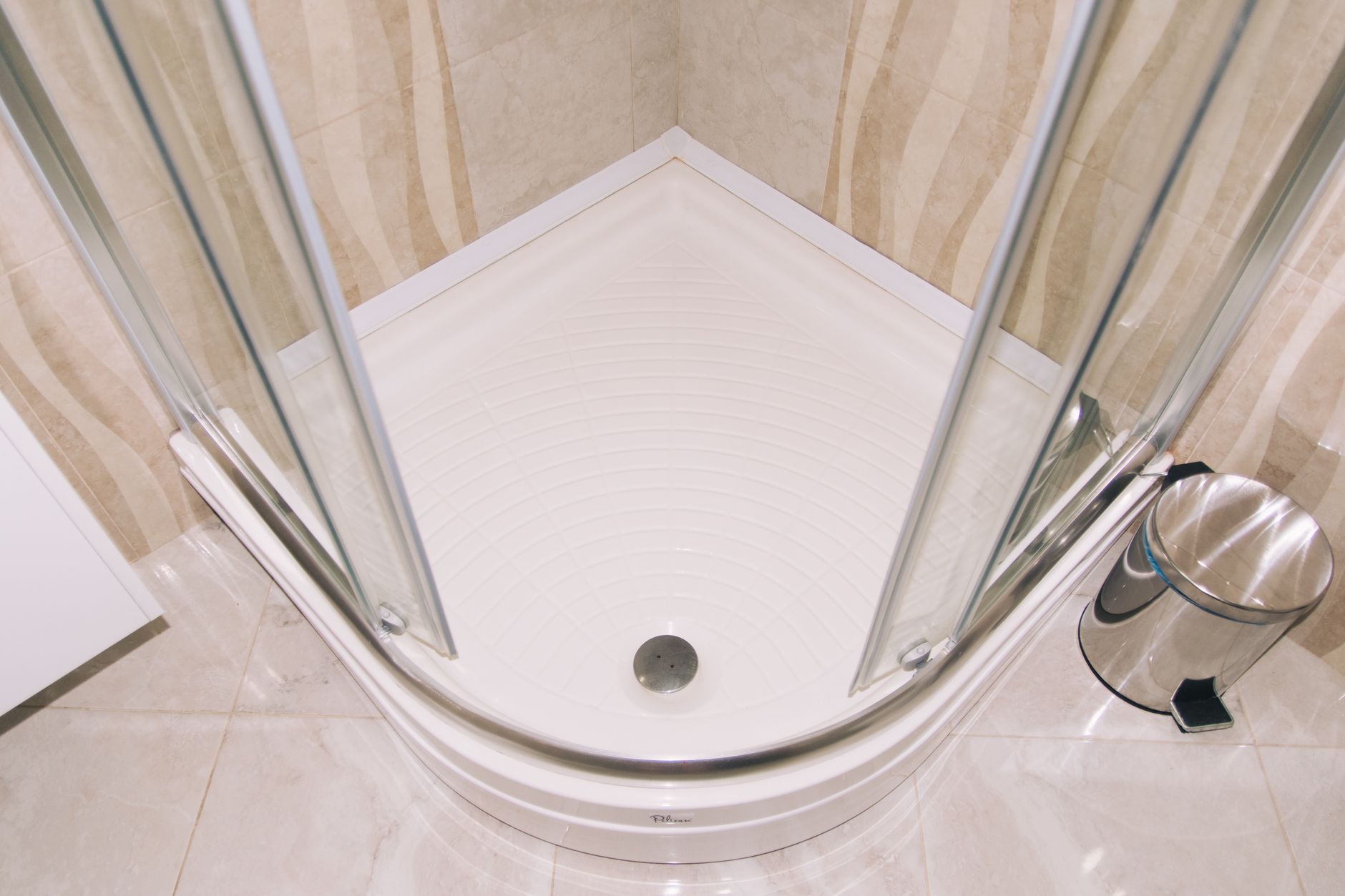 A clean, modern corner shower enclosure with glass doors in a tiled bathroom setting.
