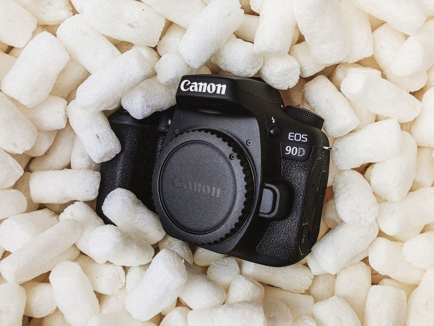 Canon DSLR camera nestled among packing peanuts, emphasizing protection and care.