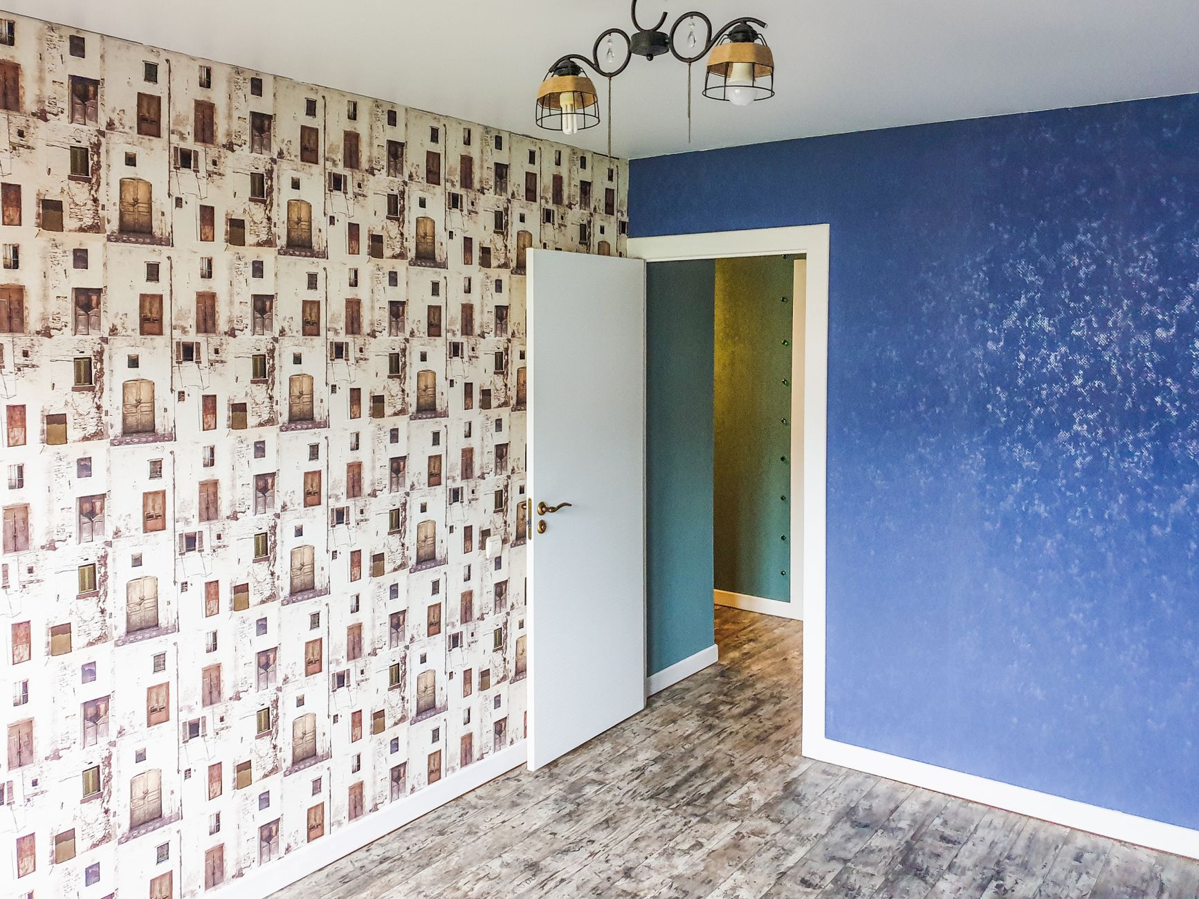 A modern room featuring a blue accent wall, unique patterned wallpaper, and contemporary lighting.