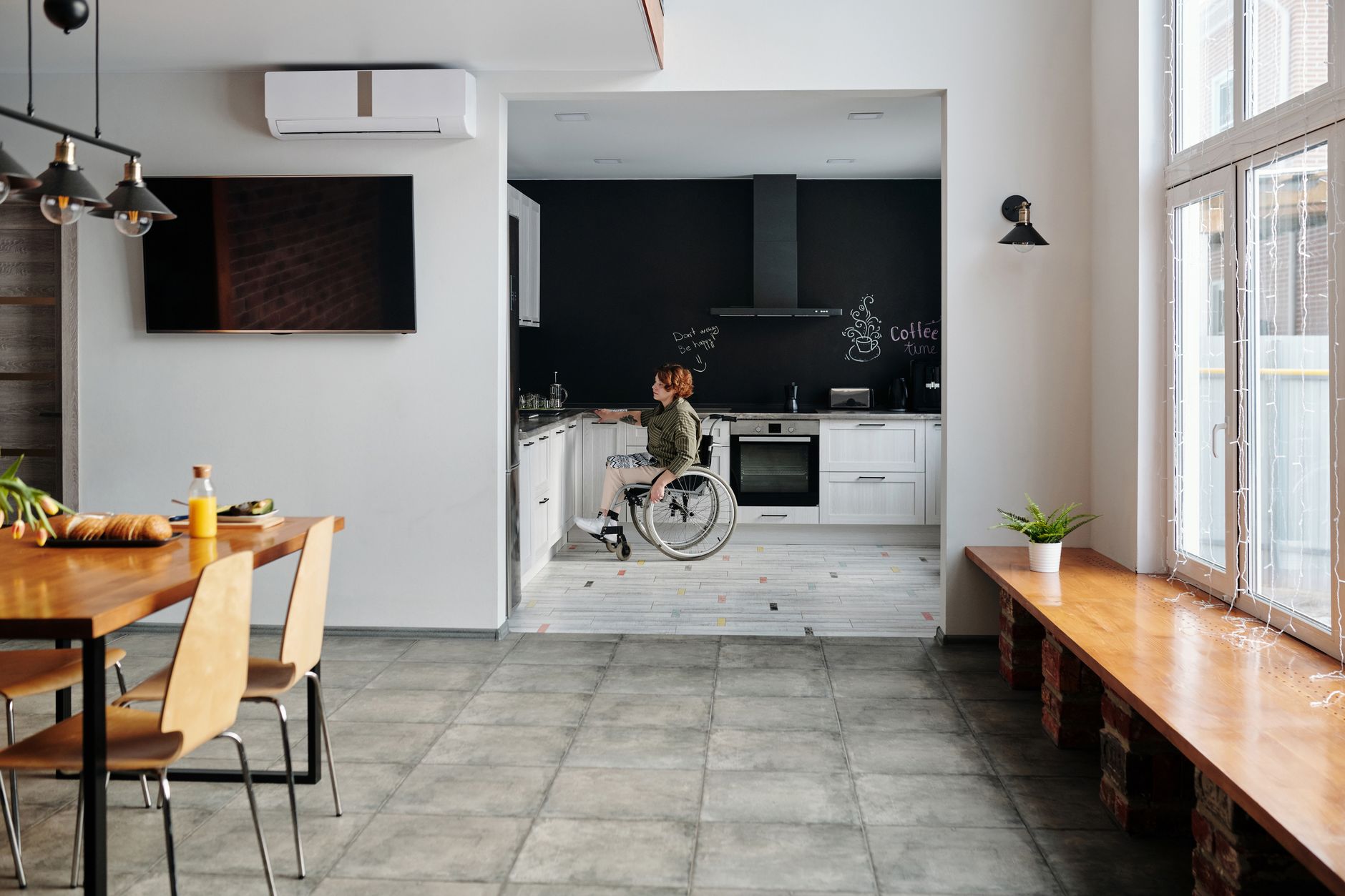 Woman in wheelchair cooking in a contemporary kitchen, sunny morning.