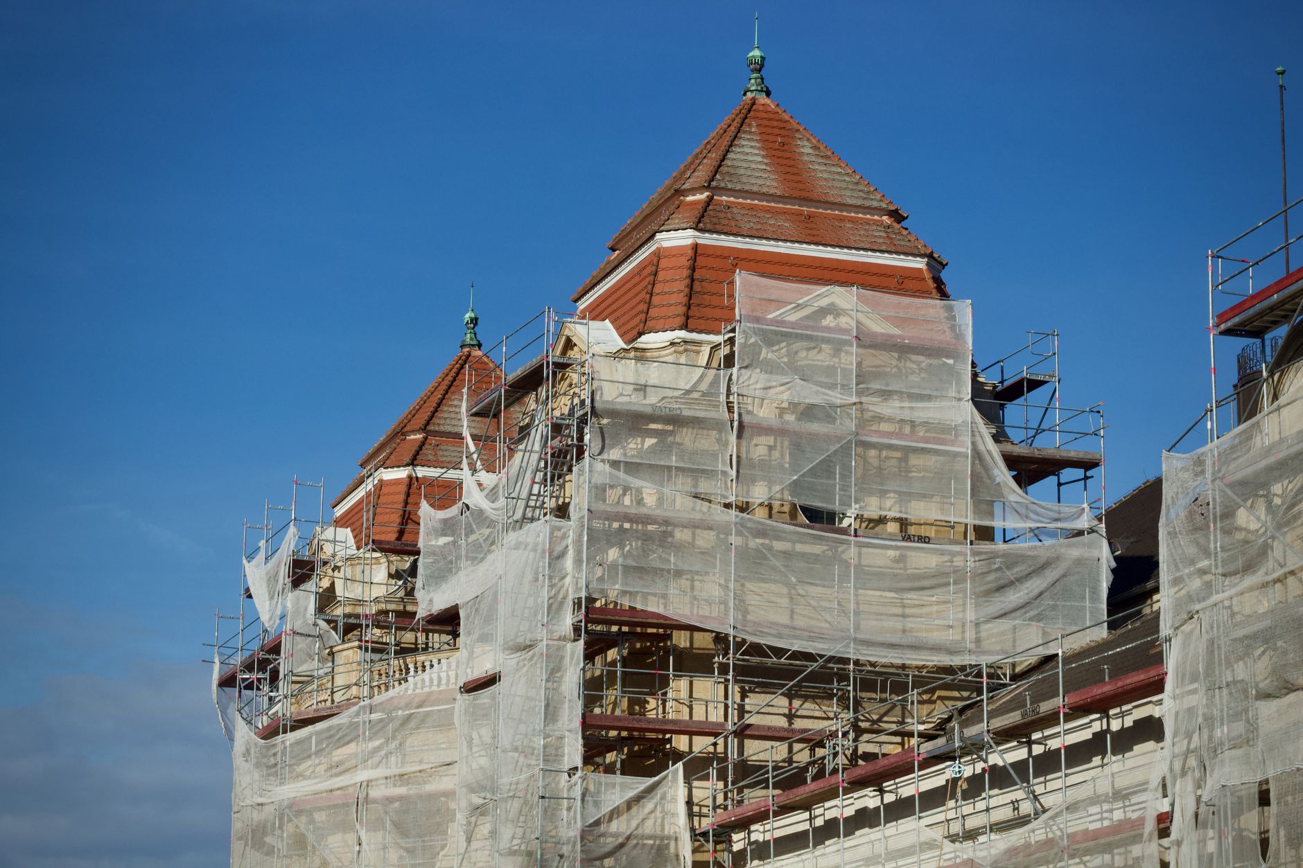 A historic building under restoration, covered in scaffolding and protective nets.
