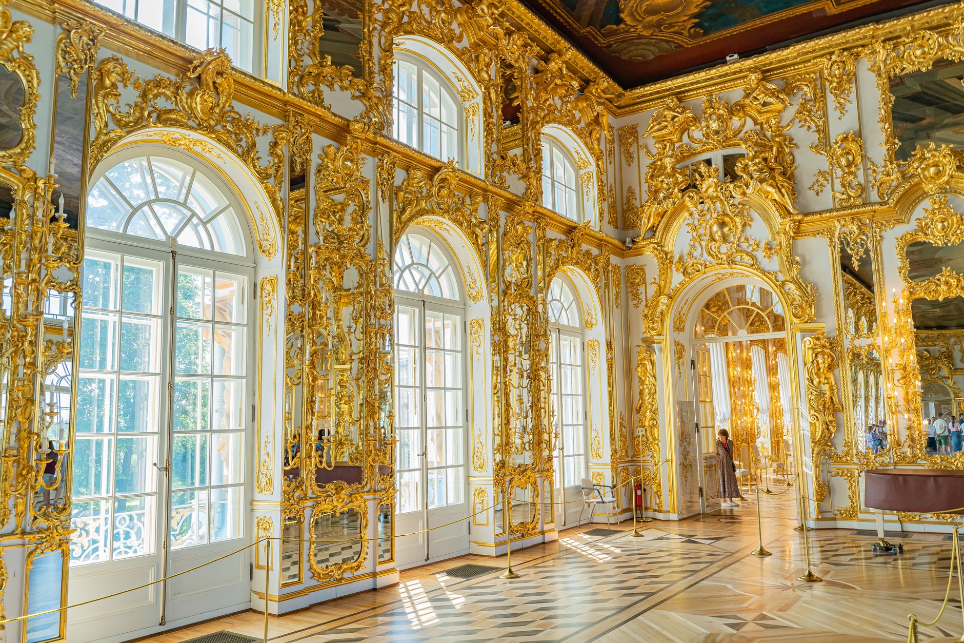 Luxurious Baroque-style room adorned with golden ornate decorations and grand arched windows.
