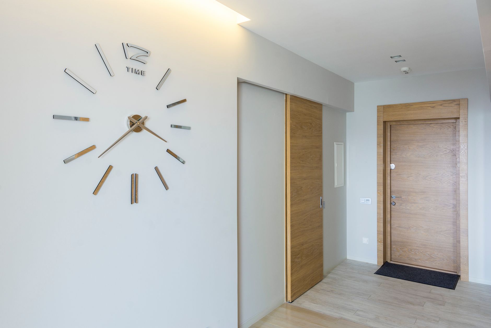 Elegant modern interior featuring a minimalist wall-mounted clock and wooden doors.