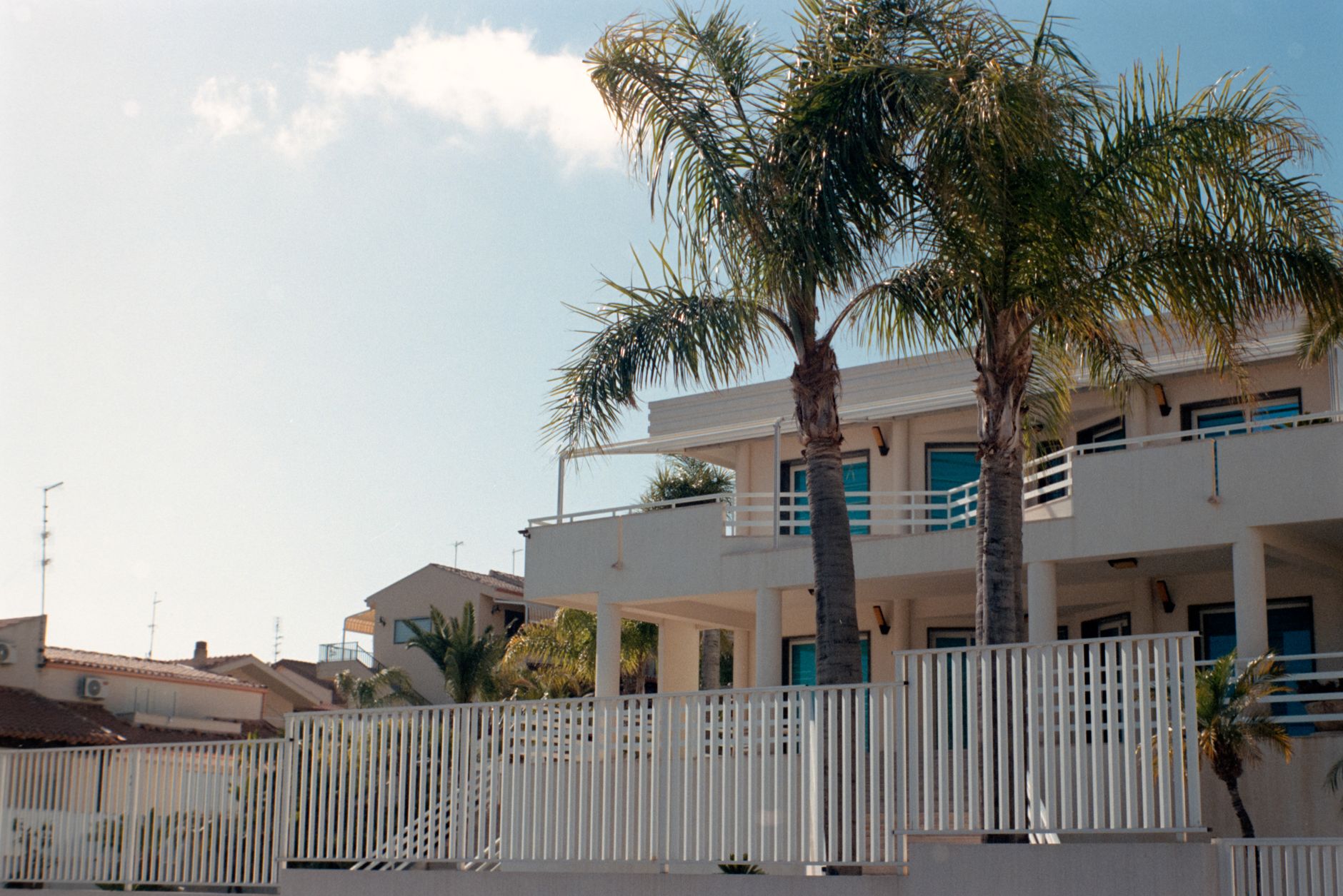 Contemporary villa with palm trees and blue sky in Sicily, Italy highlighting Mediterranean architecture.