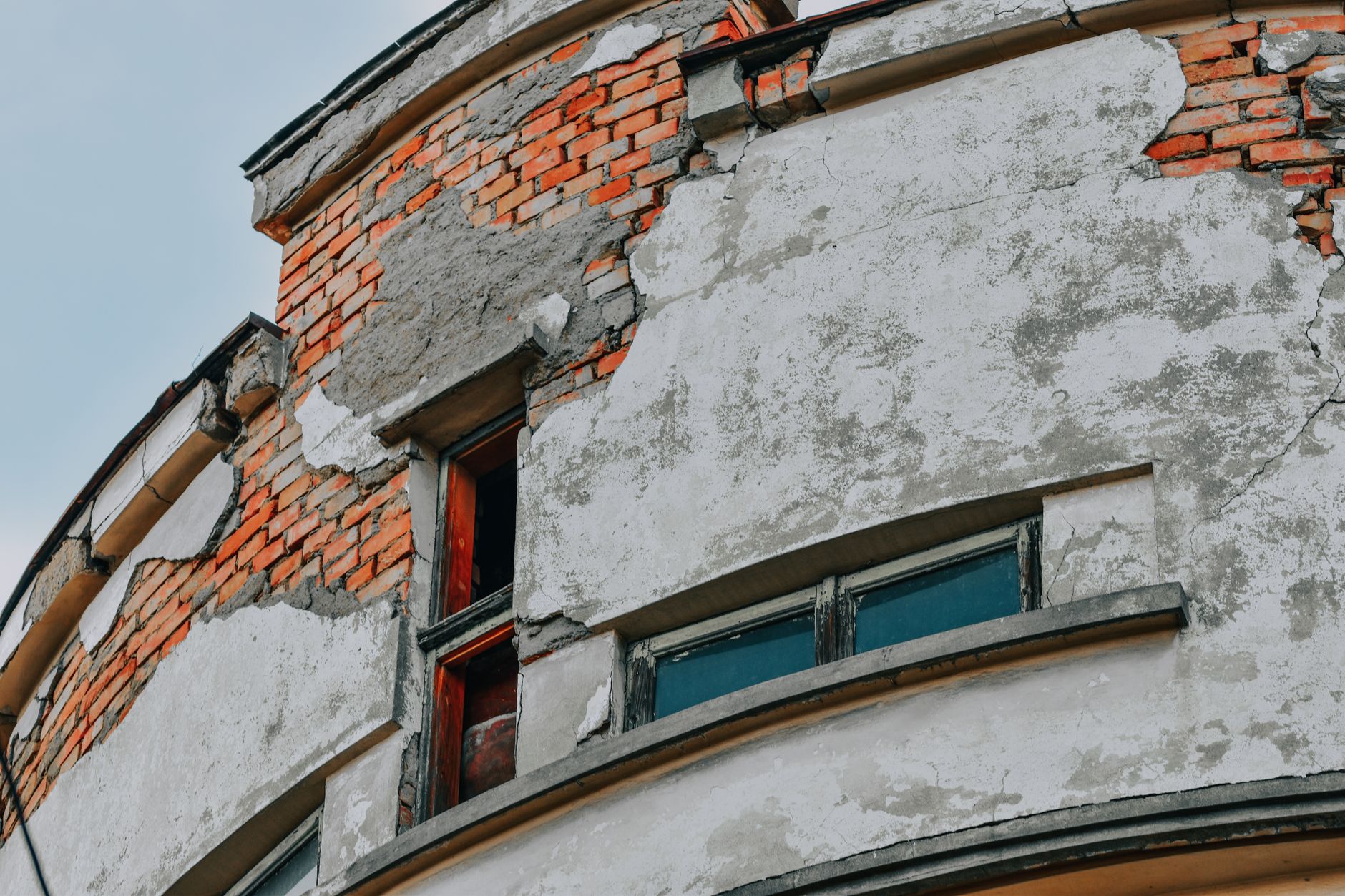 Close-up of a weathered brick building facade showing cracks and deterioration.