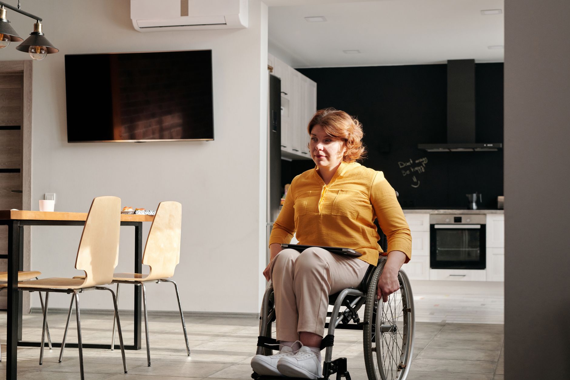 A woman in a wheelchair enjoys her accessible kitchen space, highlighting inclusive home design.