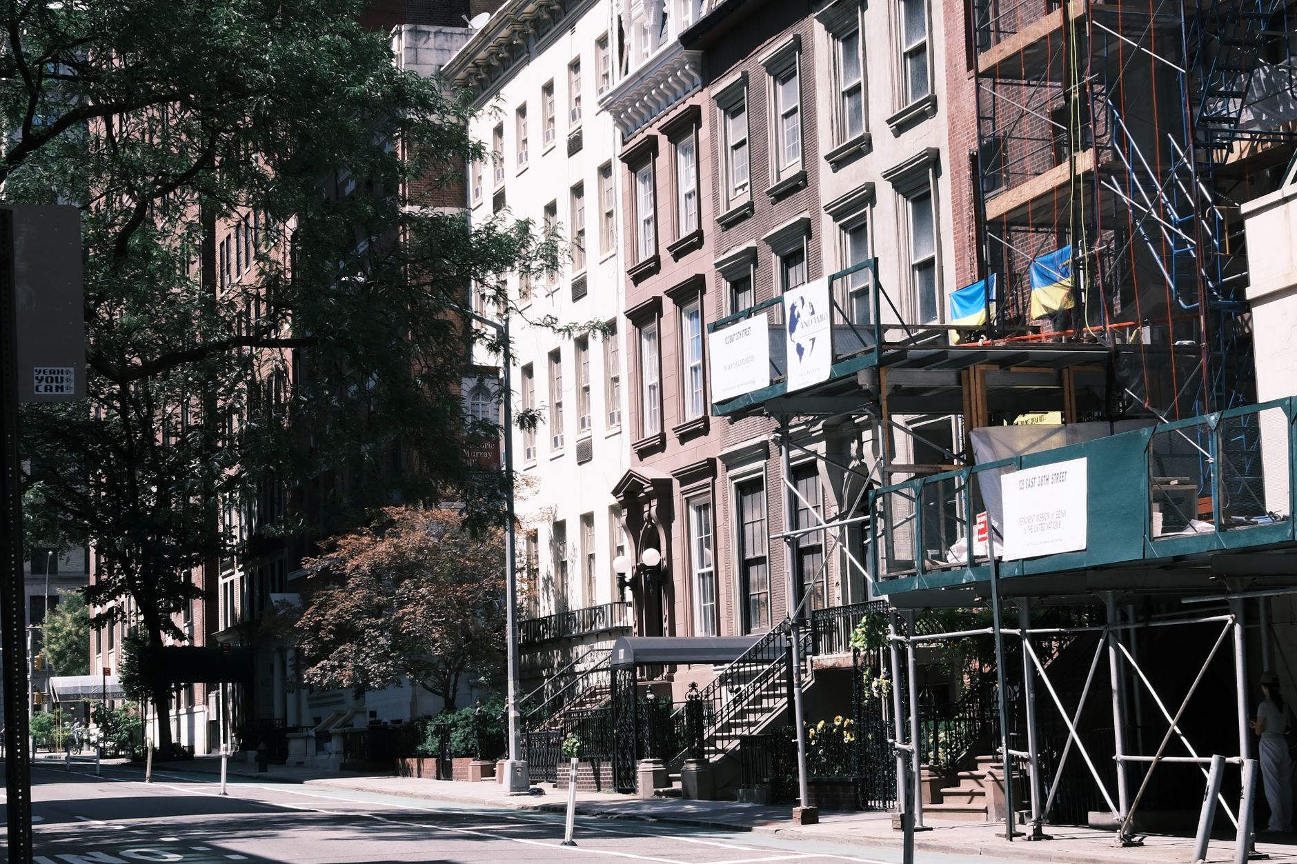 A sunny street with historic buildings and renovation scaffolding, capturing urban life.