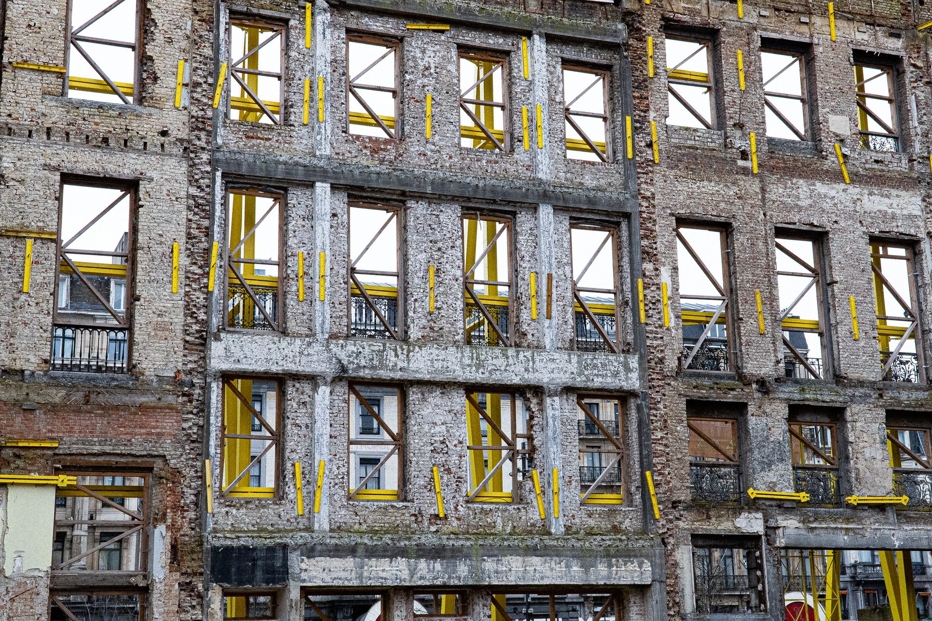 A historic building facade under renovation in urban Brussels with yellow supports.