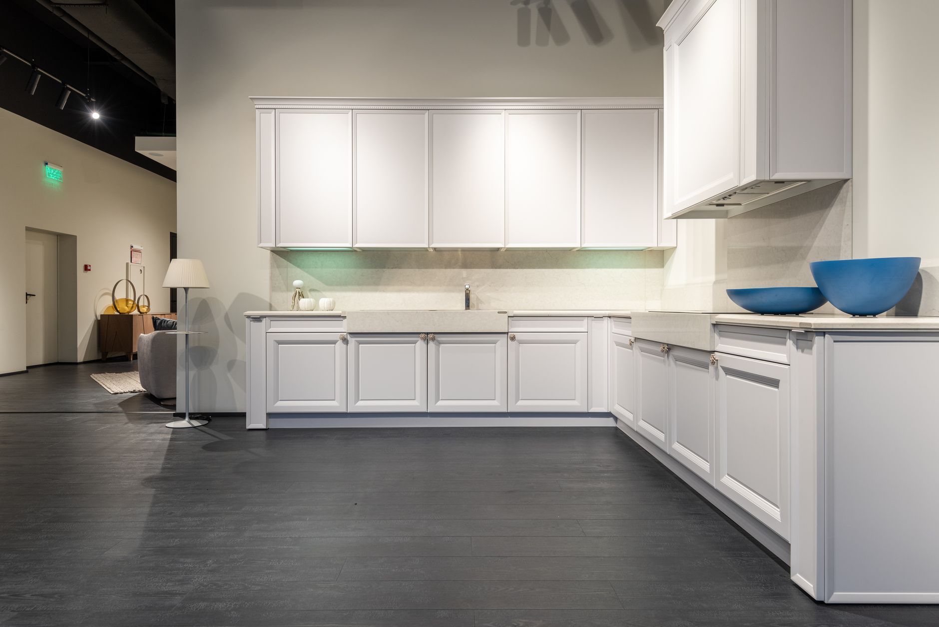 Contemporary stylish kitchen units of white color represented in modern spacious furniture showroom