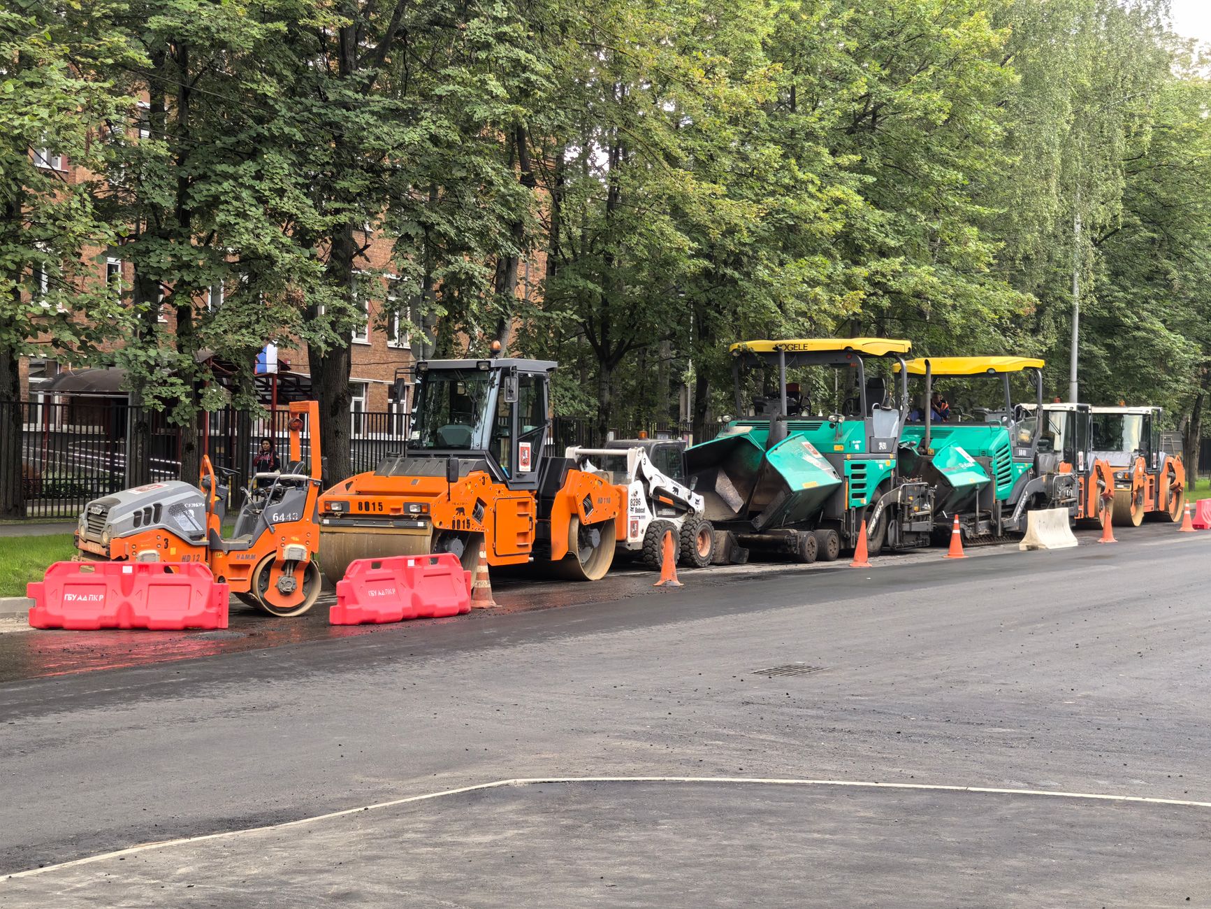Heavy machinery for roadwork lined up on an urban street during daytime construction.