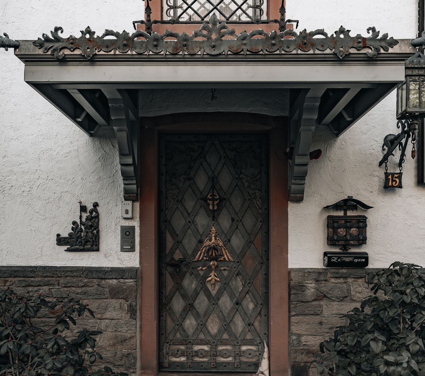 Close-up of a vintage house entrance with a detailed wrought iron canopy and ornate wooden door.