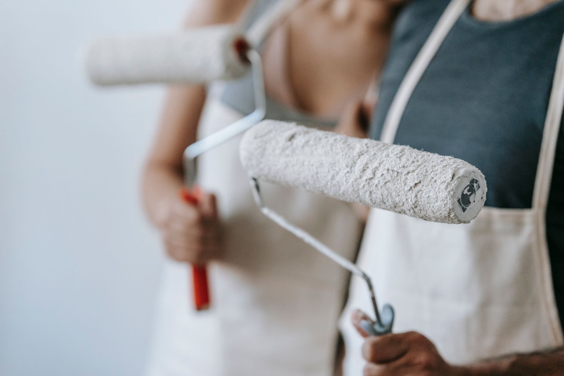 Close-up of a couple painting their new home with rollers, engaged in home improvement.