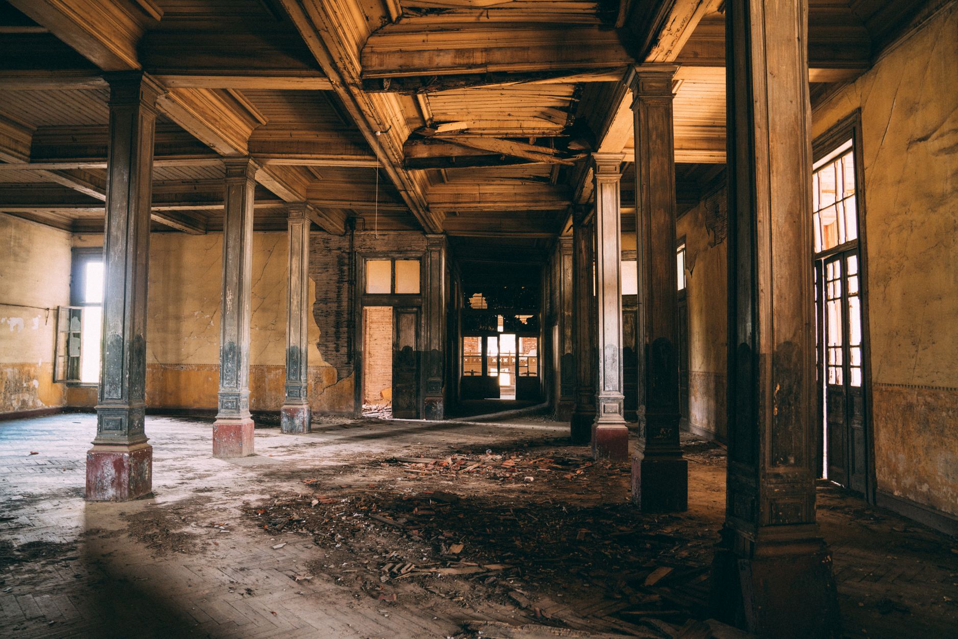 Explore an abandoned mansion interior featuring rustic wooden columns and decaying structure.