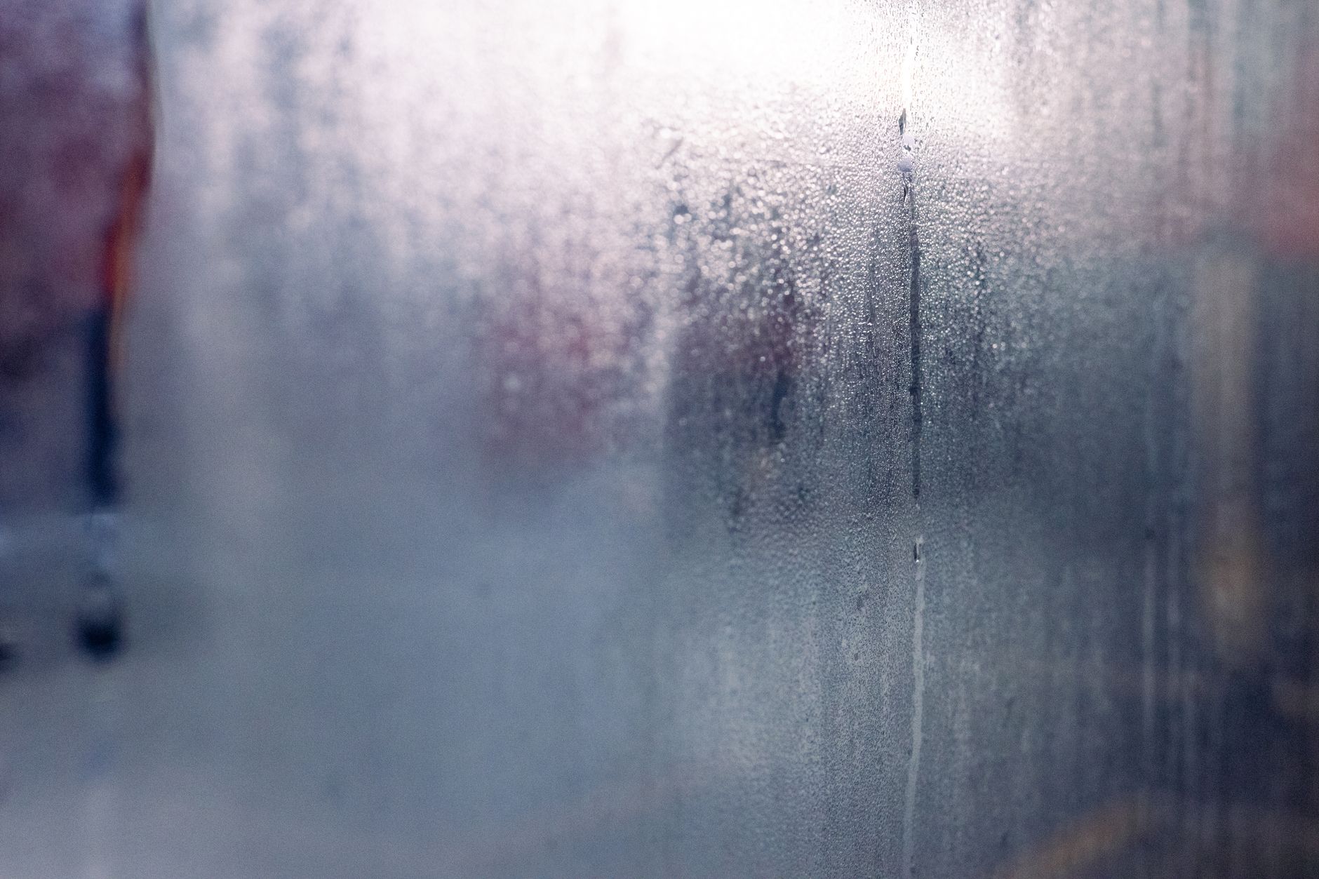 Moisture droplets on a foggy window create a mysterious and serene atmosphere.